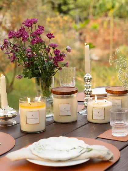 The golden glow of our lit soy candles on a rustic wooden table. This image showcases how mixing different sizes of our jar candles can create a warm and inviting centerpiece for any occasion.