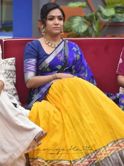 A seated view of the mustard and indigo half saree, highlighting the vibrant color of the pleated Mangalagiri silk skirt.