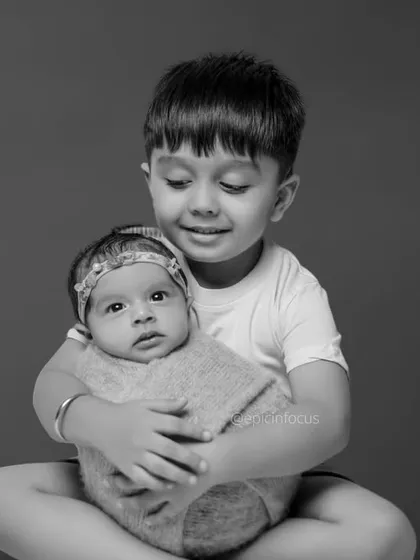 A tender moment as a big brother gently holds his newborn sibling. We specialize in capturing the delicate interactions between children.