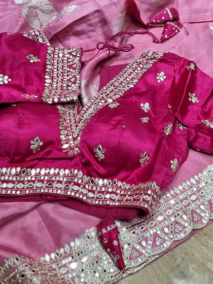 A beautiful pink saree paired with a custom-stitched blouse featuring intricate mirror work and puff sleeves. We can design and stitch the perfect blouse for any of your sarees.