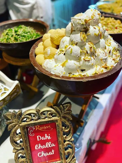 A large bowl of Dahi Bhalla Chaat, generously garnished with nuts. Our chaat counters are always a highlight, offering authentic and refreshing flavors.