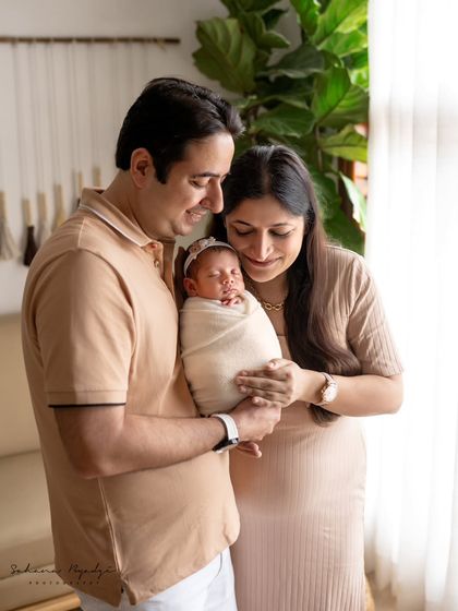 A full view of this new family, basking in the love for their newborn. The natural light from the window adds a beautiful glow.