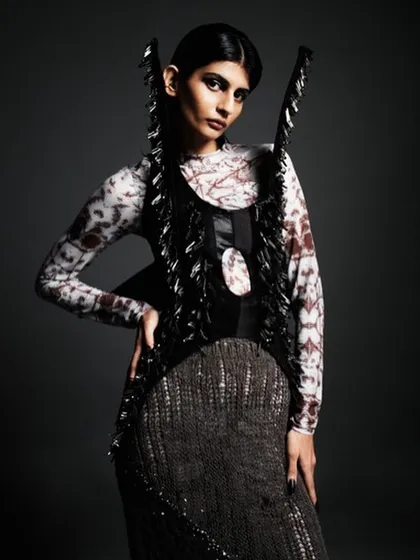 This look for a designer editorial features dramatic, dark eye makeup and a sleek, center-parted hairstyle. The entire look is built to complement the futuristic, structured fashion piece.