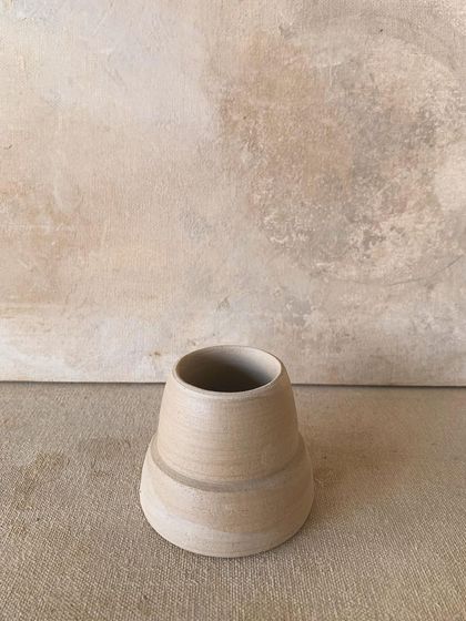 This unadorned, unfired vase stands as a testament to potential. Its beauty lies in its vulnerability and the visible traces of the maker's hands, a quiet moment before the transformative fire of the kiln.