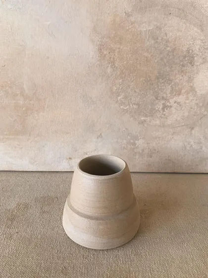 An unadorned and unfired vase. It stands as a testament to the potential seen in raw clay, beautiful in its vulnerable state.