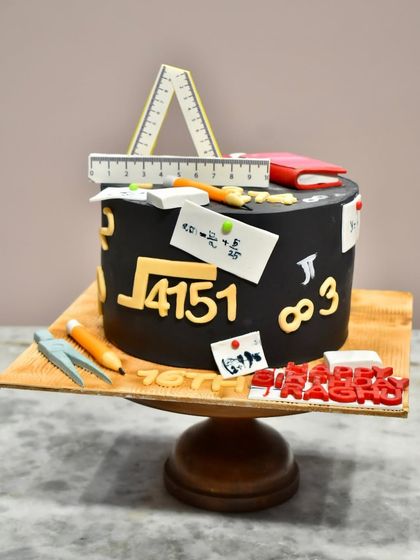 A cake for the math lover in your life. This design is styled like a chalkboard and covered in edible mathematical equations, symbols, and geometry tools like rulers and a compass.