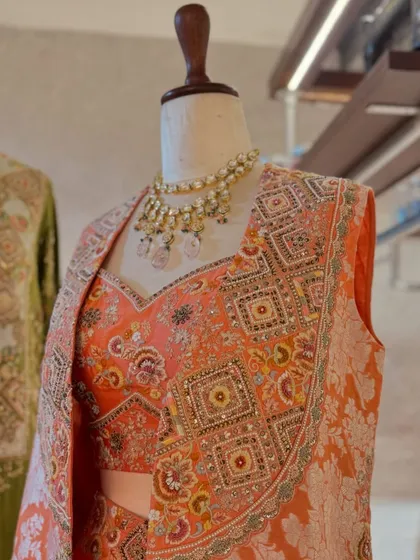 A detailed shot of the peach brocade jacket, highlighting the intricate weaving and sequin embellishments that make it a true work of art.