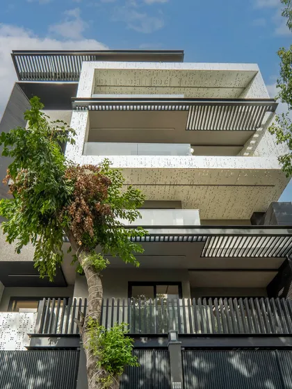 This facade design showcases sustainability and modern aesthetics. Key features include energy efficiency, durable materials like aluminum perforated jali and bricks, and a design that promotes natural ventilation for low maintenance.