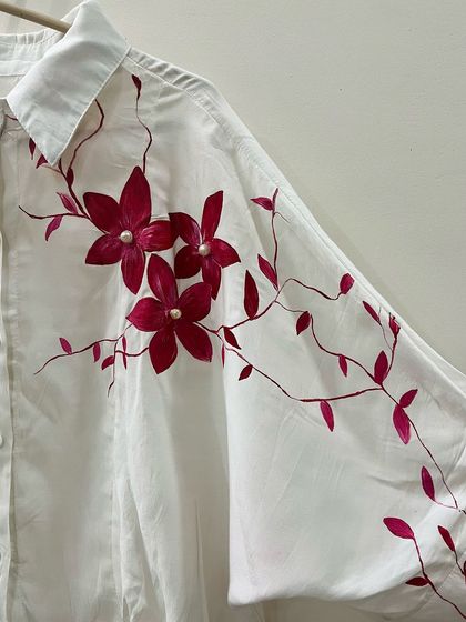For this piece, I took on a challenge to paint using only shades of red. I created these blooming flowers on a white shirt and added pearl centers for a touch of elegance.
