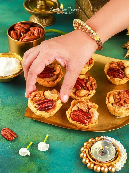 A hand delicately placing a nutty tartlet on a festive platter. This shot highlights the care and detail that goes into preparing and presenting festive sweets.