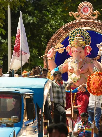 A daytime shot of the Sanpada Cha Raja procession, showing the idol being transported on a truck surrounded by organizers and devotees.