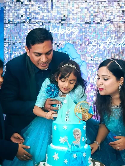 The whole family joins in to help the birthday princess blow out her candles on a stunning 'Frozen' themed cake.