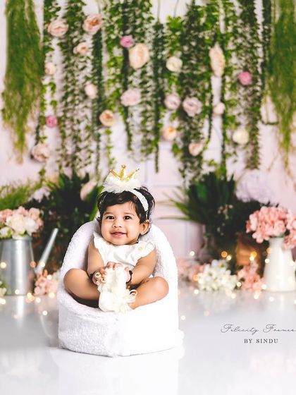 A princess in her garden. The soft lighting and hanging floral backdrop create a magical setting for this beautiful sitter milestone portrait.