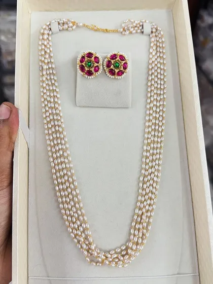A classic pearl necklace set with traditional red and green stone studs. This is a timeless piece of jewelry that every woman should have in her collection.