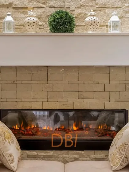 A close-up of a cozy fireplace with a stone-clad wall, creating a warm and rustic focal point in the living room. The mantelpiece is simply decorated, adding to the room's comfortable and inviting feel.