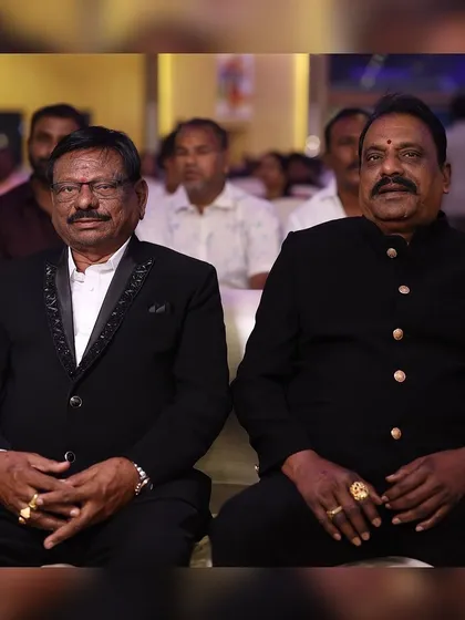 Two distinguished gentlemen at a reception, both wearing our custom-tailored suits. We cater to all ages, ensuring every family member looks their best.