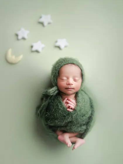 Sweet dreams in green. This minimal setup with a deep green wrap against a sage background, with moon and star props, is simple yet magical.