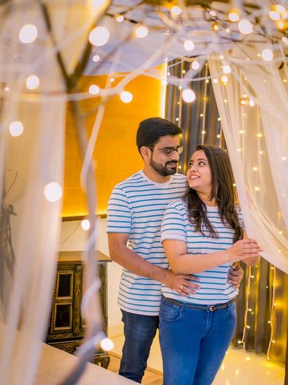 An indoor setup with a canopy bed and fairy lights creates a whimsical and cozy atmosphere for a relaxed couple's shoot.