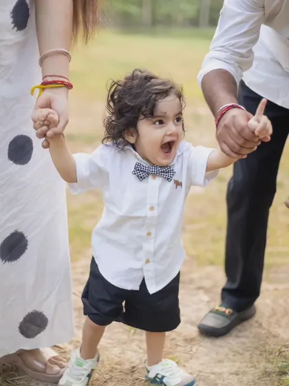 The pure excitement of a toddler taking steps with his parents' help. We capture these milestone moments during our family sessions.