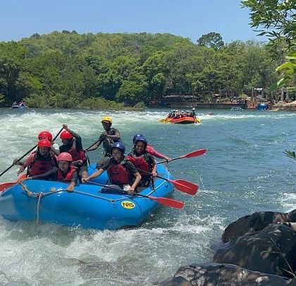 A team paddles away from a rapid, having successfully navigated the challenge together.