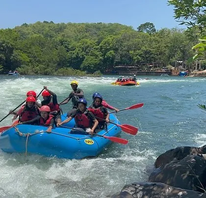 A team of young rafters navigates a turn in the river, working together to steer the boat.