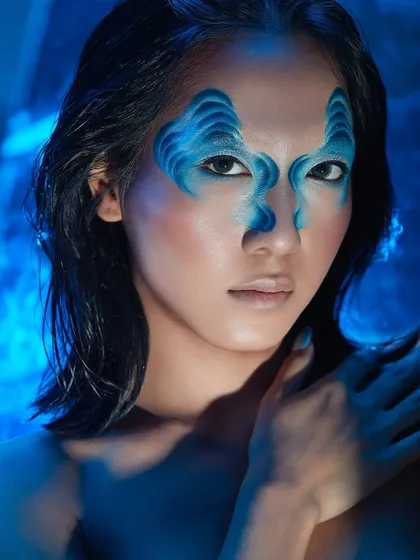 A student steps into a world of blue dreams with this creative look, featuring abstract shapes painted on the face in shades of blue.
