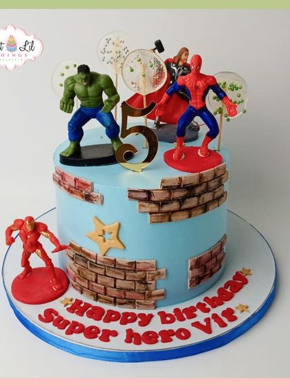 Superheroes assemble for a 5th birthday! This cake features action figures of Hulk, Spider-Man, and Iron Man on a brick-themed design.