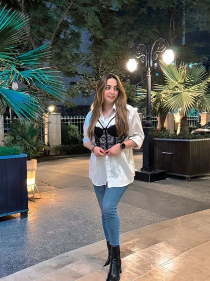 Styling a classic white shirt over a black corset top and jeans. This is a versatile look that can be dressed up or down for any occasion.