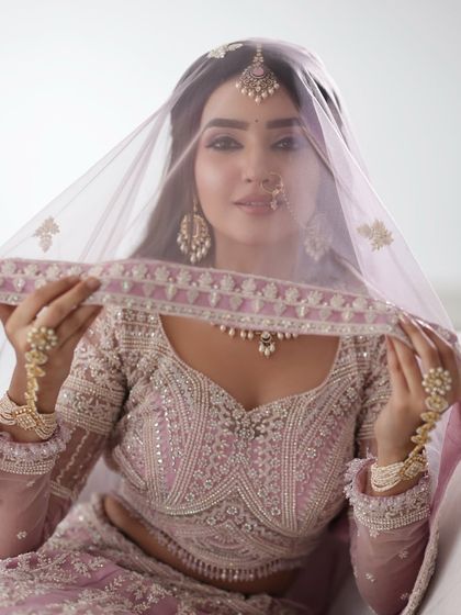 A classic shot with the veil, creating a soft and ethereal look. The makeup is visible through the sheer fabric, looking flawless.