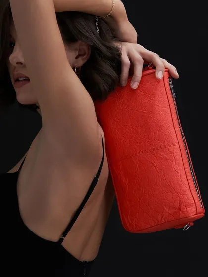 While the focus is the bag, this shot also captures a mood of understated elegance that is central to beauty and fashion photography. The soft lighting on the model's skin and the pop of color from the bag create a beautiful contrast.