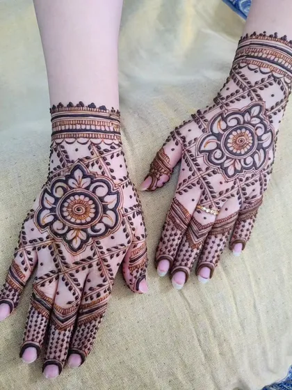 A lovely Eid henna design with a central floral mandala. The pattern spreads out across the hand with a net-like design, giving it a delicate and intricate feel.