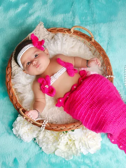 This little mermaid strikes a cute pose in her wicker basket. The turquoise background and pearl details complete the magical under-the-sea vibe.