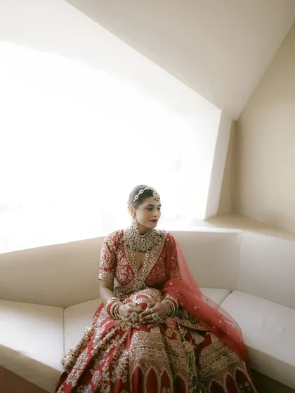 A pensive bridal portrait, with the bride sitting by a window. The bright, soft light creates a serene and thoughtful mood.