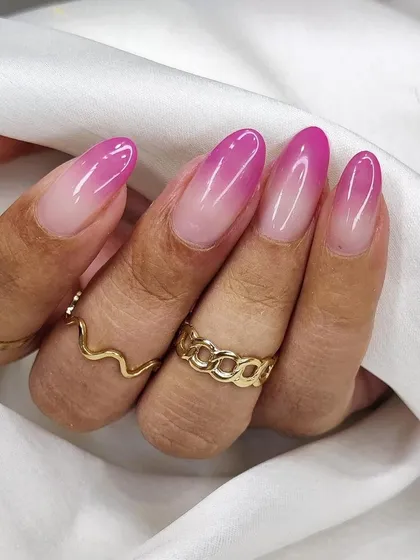 A beautifully blended pink ombré on almond-shaped nails. This gradient nail art transitions smoothly from a soft nude base to a vibrant magenta tip, creating a fresh and polished look.