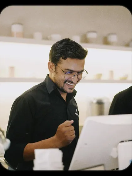 Even our team gets in on the fun! A happy staff member at the counter, enjoying the cafe's vibrant energy.