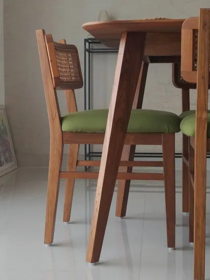 A detail of our custom-designed dining set, showcasing the intersection of material and form. The chair combines the warmth of teak wood and woven rattan with a clean, modern geometry, reflecting our commitment to handcrafted quality and timeless design in residential furniture.