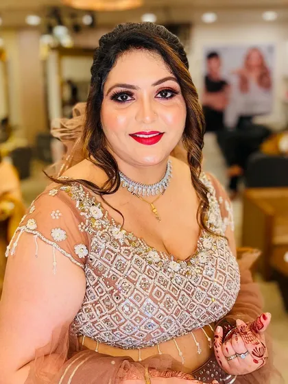 A happy and glowing client ready for an engagement party. Her makeup features a classic red lip and soft, defined eyes, paired with a simple hairstyle that lets her outfit shine.