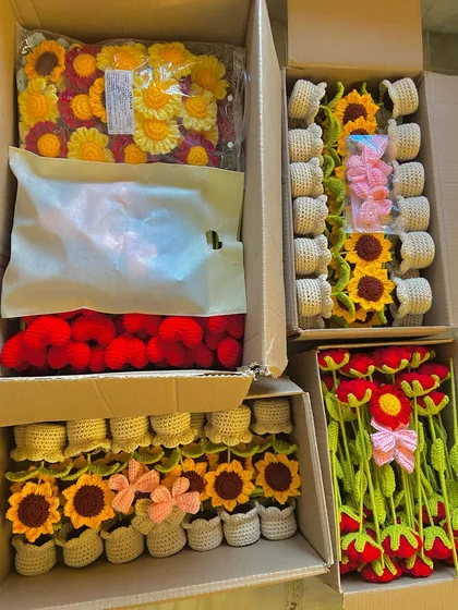 An overhead view of four open boxes, filled with a large wholesale order of potted sunflowers, hearts, and stems.