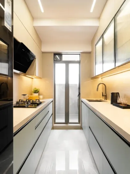A full view of a contemporary galley kitchen designed for efficiency. The layout ensures everything is within easy reach, while the light color palette and reflective flooring make the space feel larger.