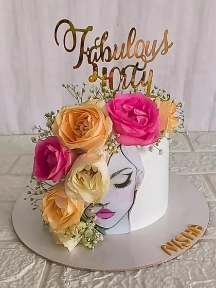 A stunning cake for a "Fabulous Forty" birthday. This design features a hand-painted portrait on an edible sheet, crowned with a beautiful arrangement of fresh peach and pink roses.
