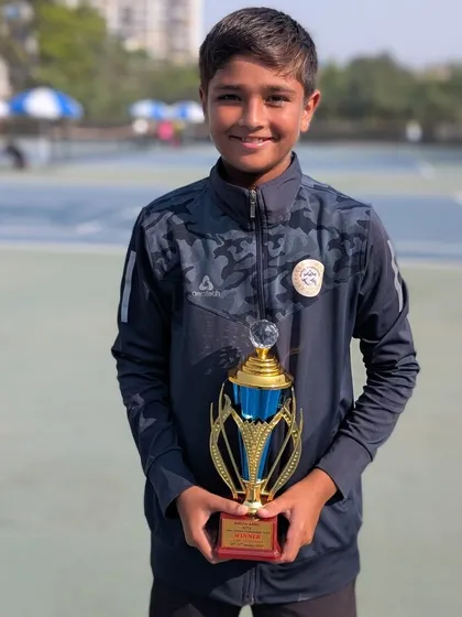 Aarav in his academy jacket with the U-16 doubles trophy.