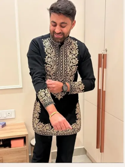 A happy client in a custom black short kurta with heavy gold embroidery.