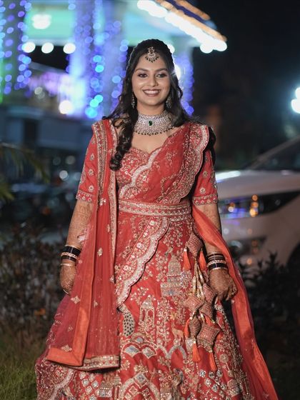 A full-length shot of Amrutha looking radiant and happy at her reception. Her red lehenga and glamorous makeup make for a show-stopping bridal look.
