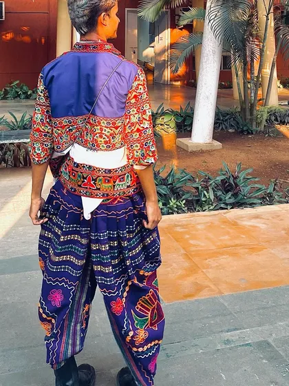 A view from the back, showing the detailed embroidery on the Kedia jacket and the unique pattern of the dhoti pants.