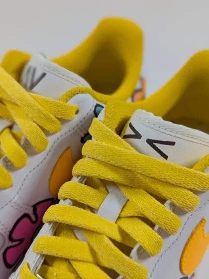 A close-up on the details of the floral customs, including the bright yellow laces and custom tongue tag.