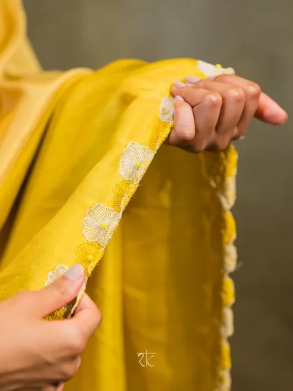 A close-up of the lime and ivory half saree's border, showcasing the delicate, handcrafted floral threadwork that runs along the edge.