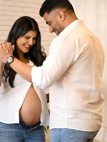 A joyful and candid maternity shot of a couple dancing together in the studio. Their smiles capture the happiness of this special journey.