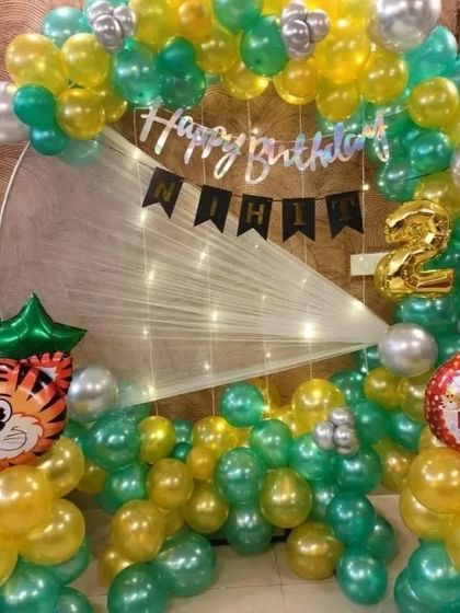 A jungle-themed 2nd birthday with a circular backdrop, featuring a tiger foil balloon and green and yellow balloons.