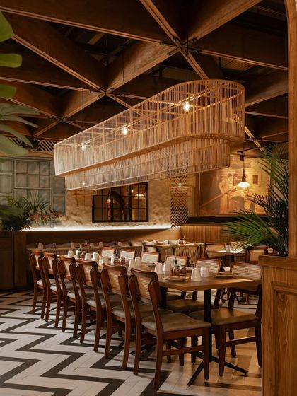 A large, custom-made cane light fixture hangs over the main dining area, creating a dramatic focal point.