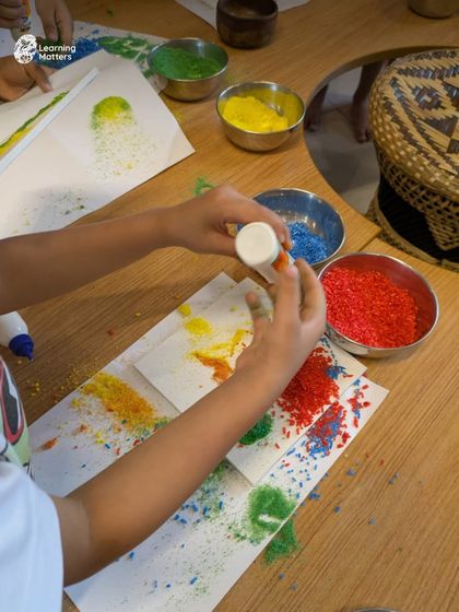 Using glue and vibrantly colored rice, this child is engaged in a multi-sensory art experience. This process develops fine motor control, hand-eye coordination, and an understanding of texture and adhesion, all while creating a unique piece of process art.